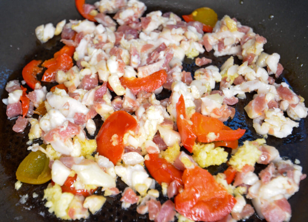 Pancetta, cherry peppers, garlic, and olive oil frying together 